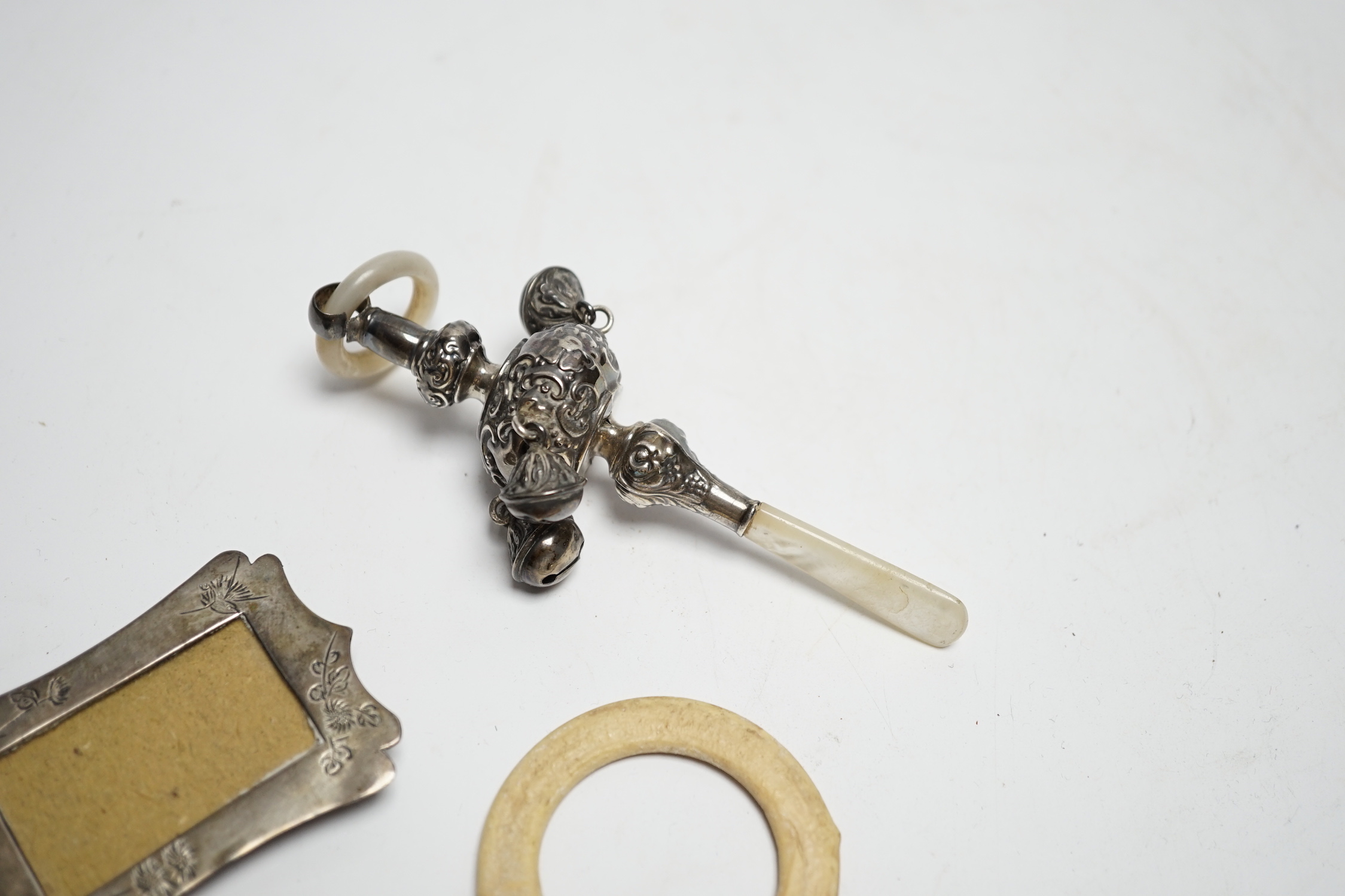 An Edwardian silver and mother of pearl child's rattle, 11cm, together with a miniature white metal photograph frame and a plated child's rattle.